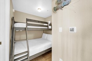 A bunk bed with a wooden frame and white bedding. There is a ceiling light and a wall-mounted light switch. - Tidewater 2112 (Panama City Beach)