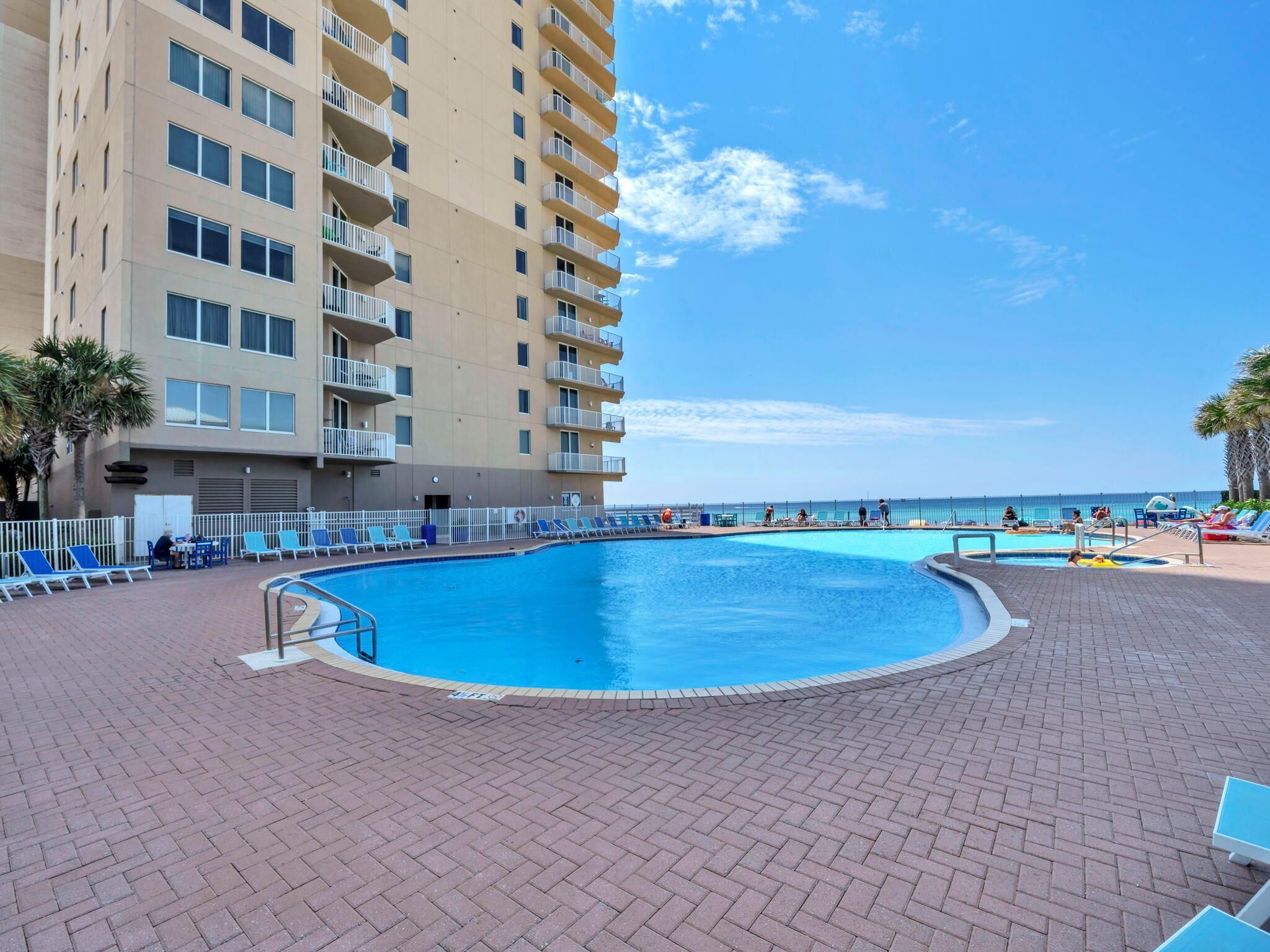 Un espace piscine avec des chaises longues et un bâtiment doté de balcons.