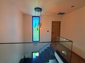 Ein modernes Interieur mit Glastrennwand, Holztür und Blick durch ein Fenster.