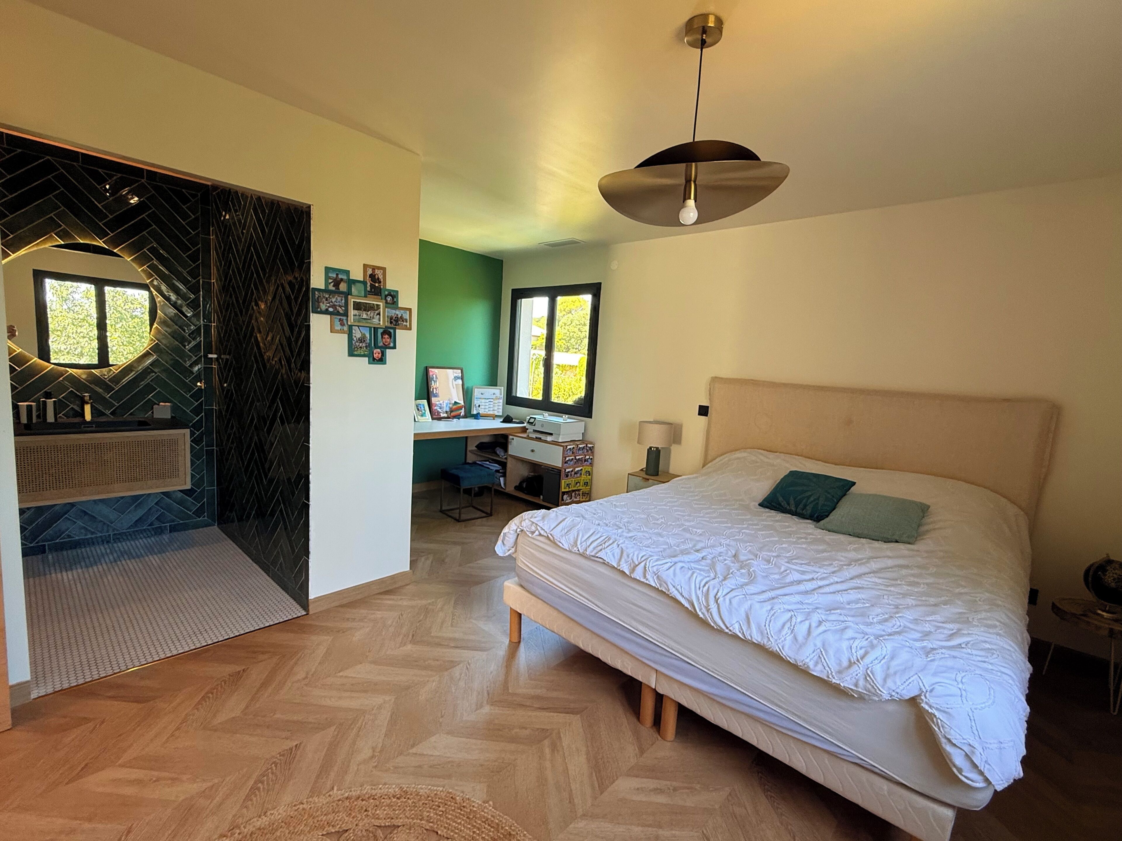 Une chambre avec un grand lit, un bureau et une salle de bain équipée d’un meuble-lavabo.