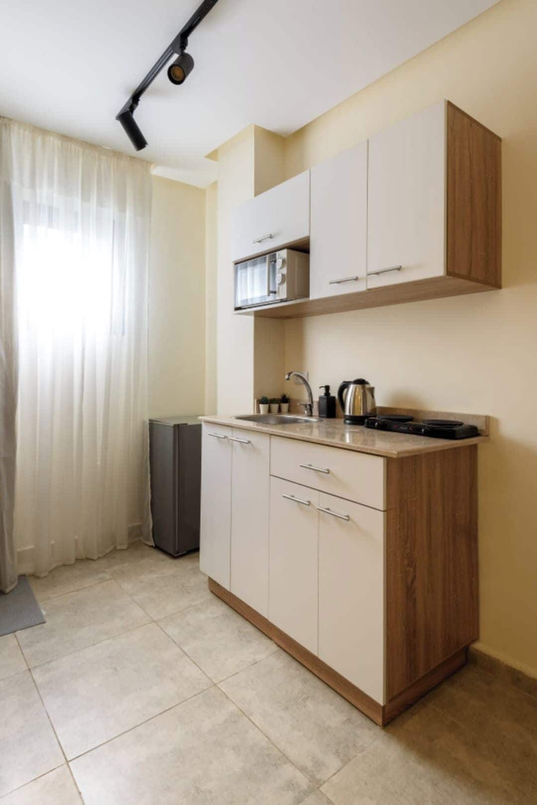A compact kitchen with a microwave, sink, and cabinets.