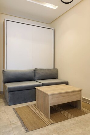 Una sala moderna con un sofá gris, una mesa de centro de madera y una alfombra estampada.