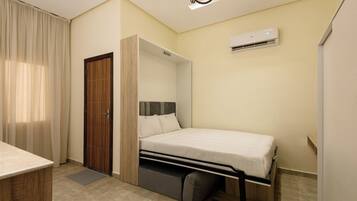 Una habitación pequeña con cama, armario y aire acondicionado.