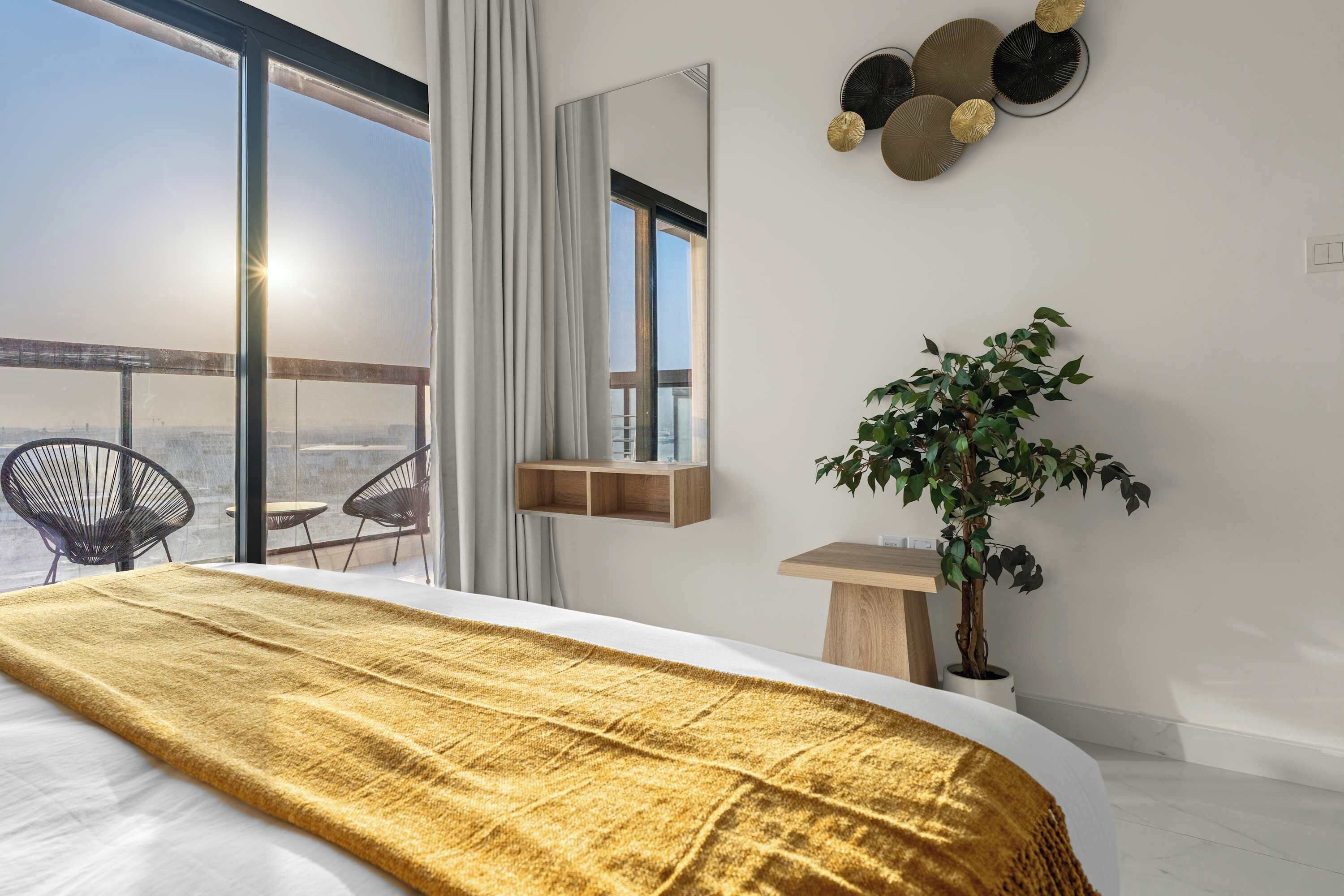 Ein modernes Schlafzimmer mit einem großen Bett, Blick auf die Stadt, einem Balkon und einer Pflanze.