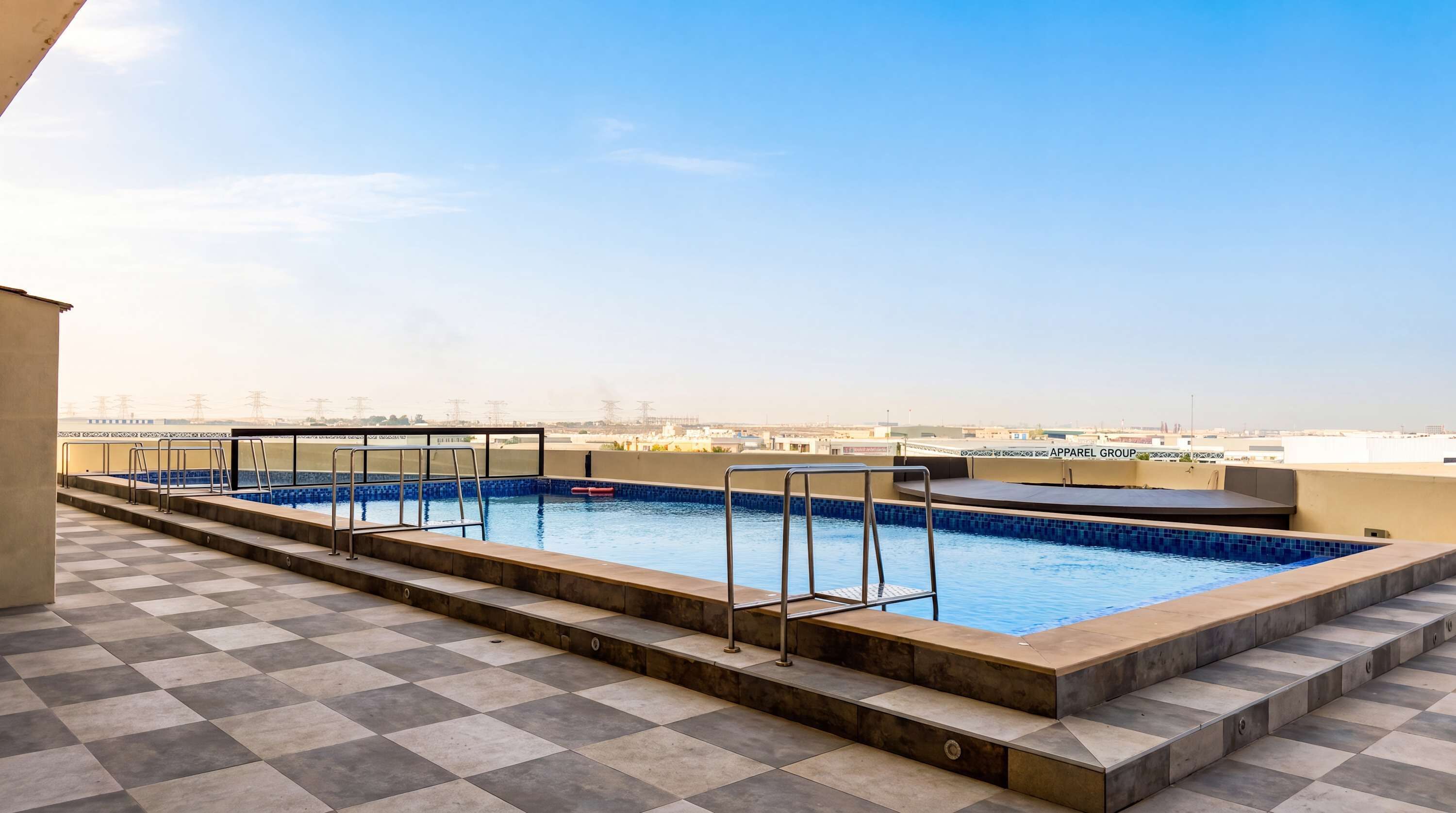 A rooftop swimming pool with clear blue water, a tiled deck, and a view of the city skyline.