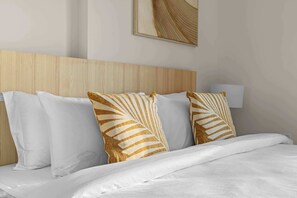 A neatly made bed with white bedding and decorative pillows with a leaf pattern. - 1BR near Expo City with Pool, Gym & Basketball (Jebel Ali)