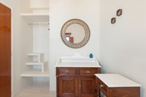 A bathroom with a wooden vanity, a round mirror with a decorative frame, and a white sink. - The San Villa with Caldera Sea View and Private Hot Tub in Oia (Oia)