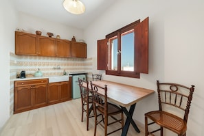 A kitchen with wooden cabinets, a dining table, and chairs. - The San Villa with Caldera Sea View and Private Hot Tub in Oia (Oia)