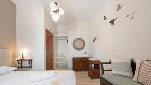 Quarto de hotel com duas camas, uma escrivaninha, cômoda, espelho e escada para um andar superior.