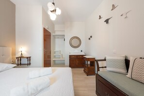 Ein Hotelzimmer mit zwei Betten, einem Schreibtisch, einer Kommode, einem Spiegel und einer Treppe, die zu einer oberen Etage führt.
