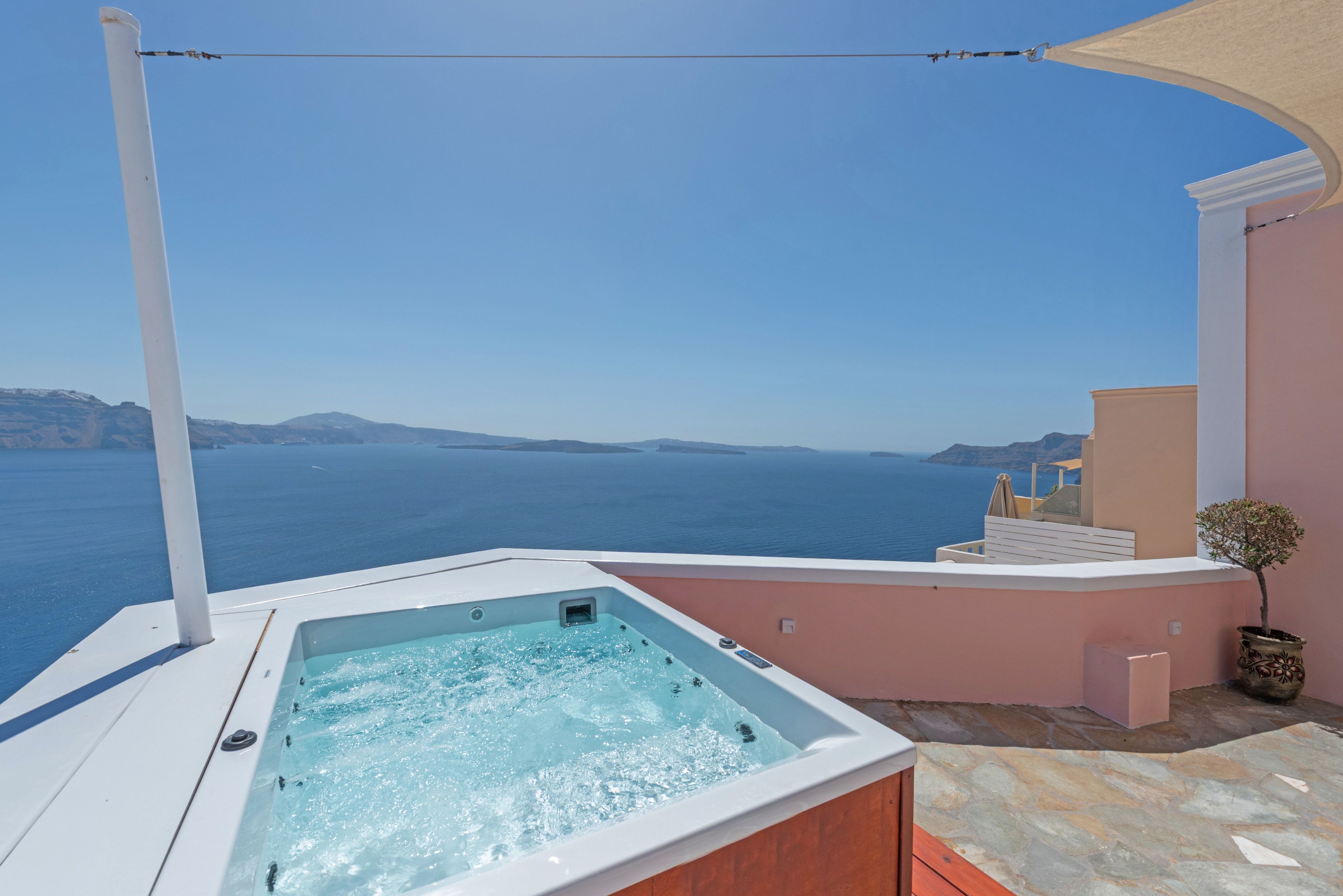 A hot tub on a balcony overlooking a sea view.