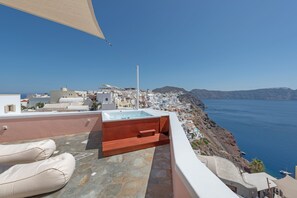 Eine Dachterrasse mit Whirlpool, Sitzgelegenheit und Blick auf eine Küstenstadt.