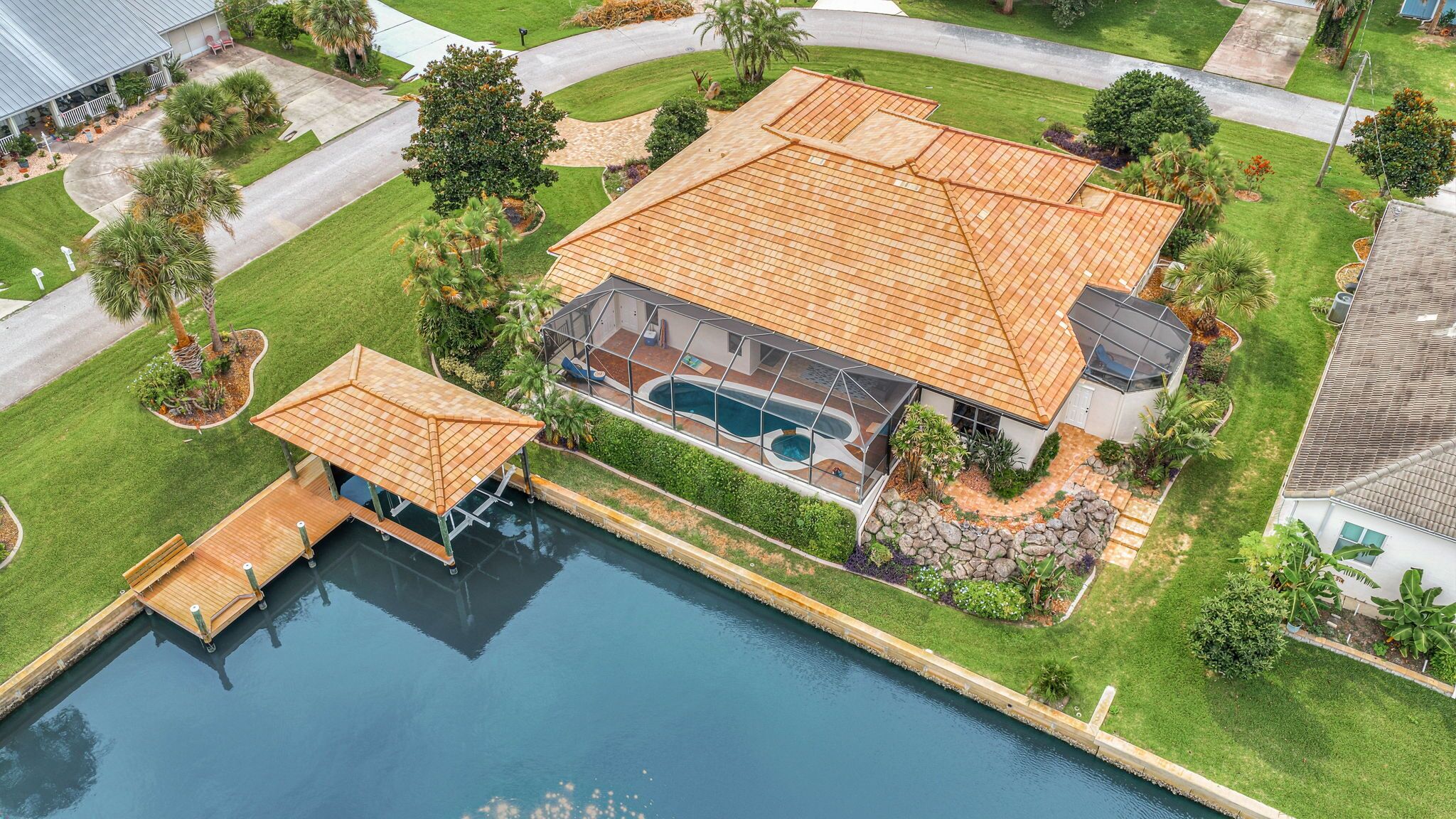 Una casa grande con piscina, muelle y césped bien cuidado.