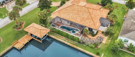 Una casa grande con piscina, muelle y césped bien cuidado.