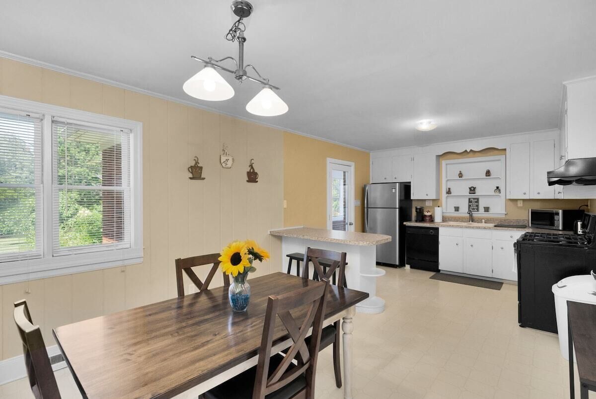 A kitchen with a dining table, chairs, a refrigerator, a microwave, and a stove.