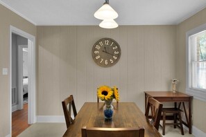 A dining area with a wooden table, chairs, a wall clock, and a vase with sunflowers. - Cozy Pet Friendly Home with Private Backyard (Charlotte)