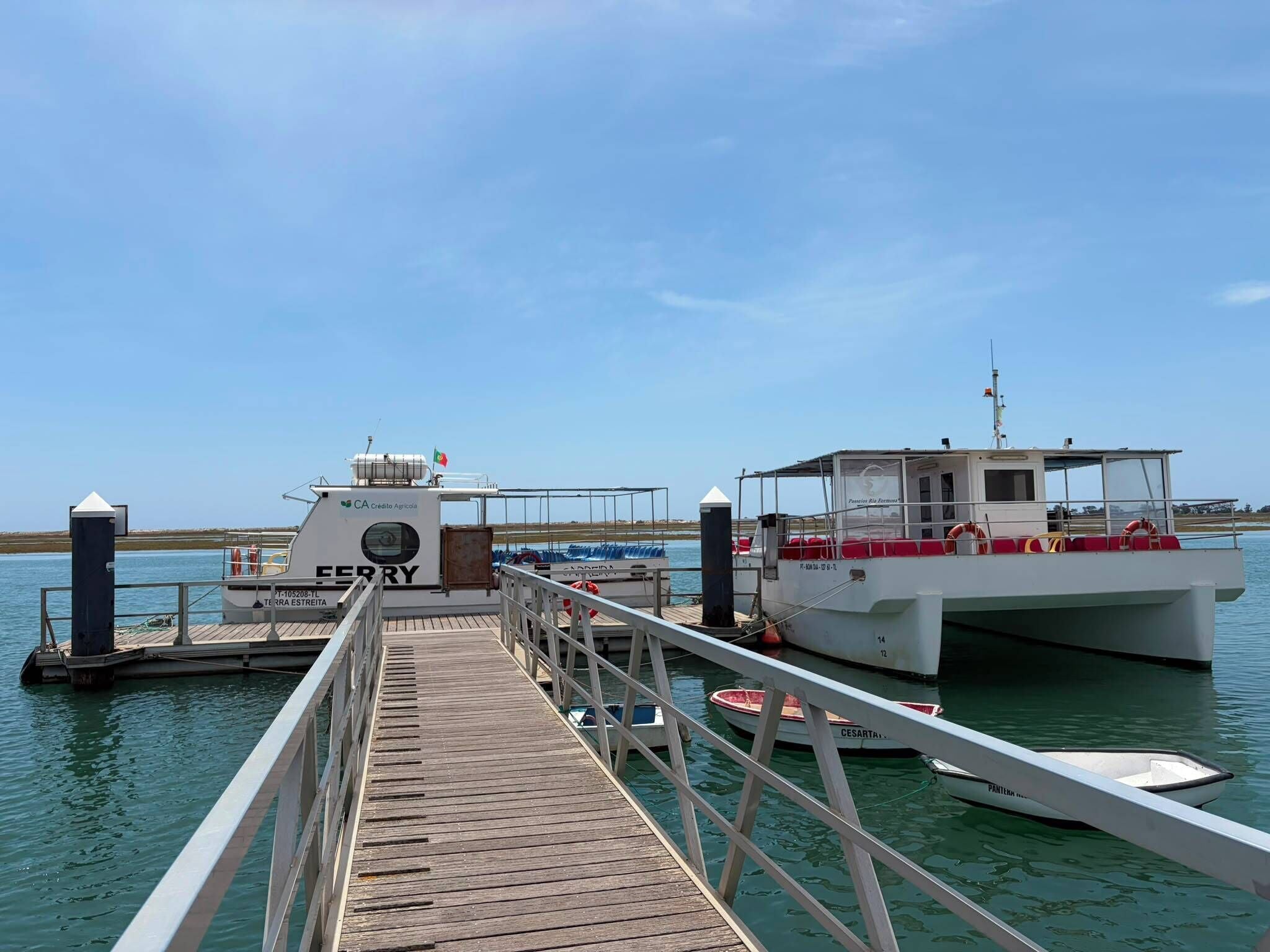 A dock with a wooden walkway leading to a white boat with red accents and a smaller boat docked nearby.