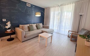A modern living room with a sofa, a coffee table, and a map wall. - Charming Apt 1BR - Private Balcony & Bay View (Hallandale Beach)