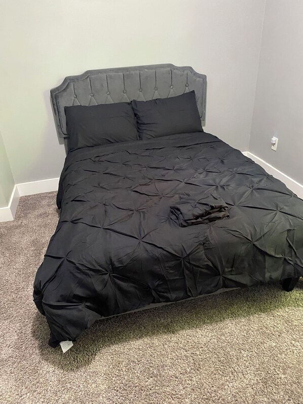 A bed with a tufted headboard and a black bedspread.