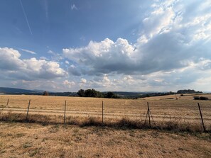 A rural landscape with a field, fence, and distant hills.