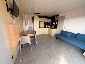 A compact living space with a kitchenette, a dining area, and a sofa.