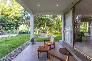 A covered patio with a seating area, a small table, and a bench. - ONA Garden Villa: Deluxe Double Room (Galle)