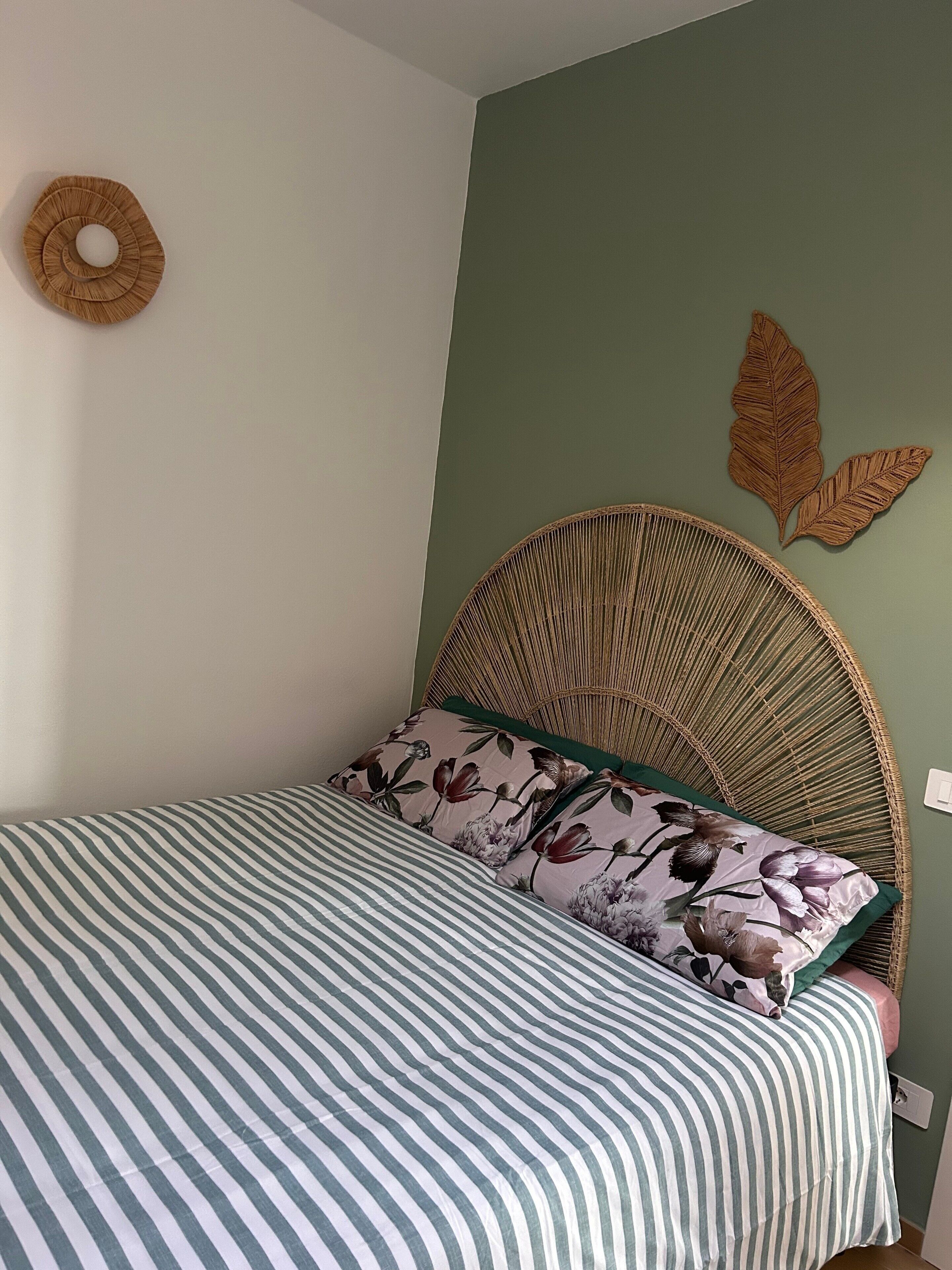 Ein Bett mit einer gestreiften Bettdecke, einer runden Wanddekoration und einer blattförmigen Wanddekoration.