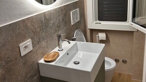 Ein Badezimmer mit Waschbecken, Spiegel, Fenster und Toilette.