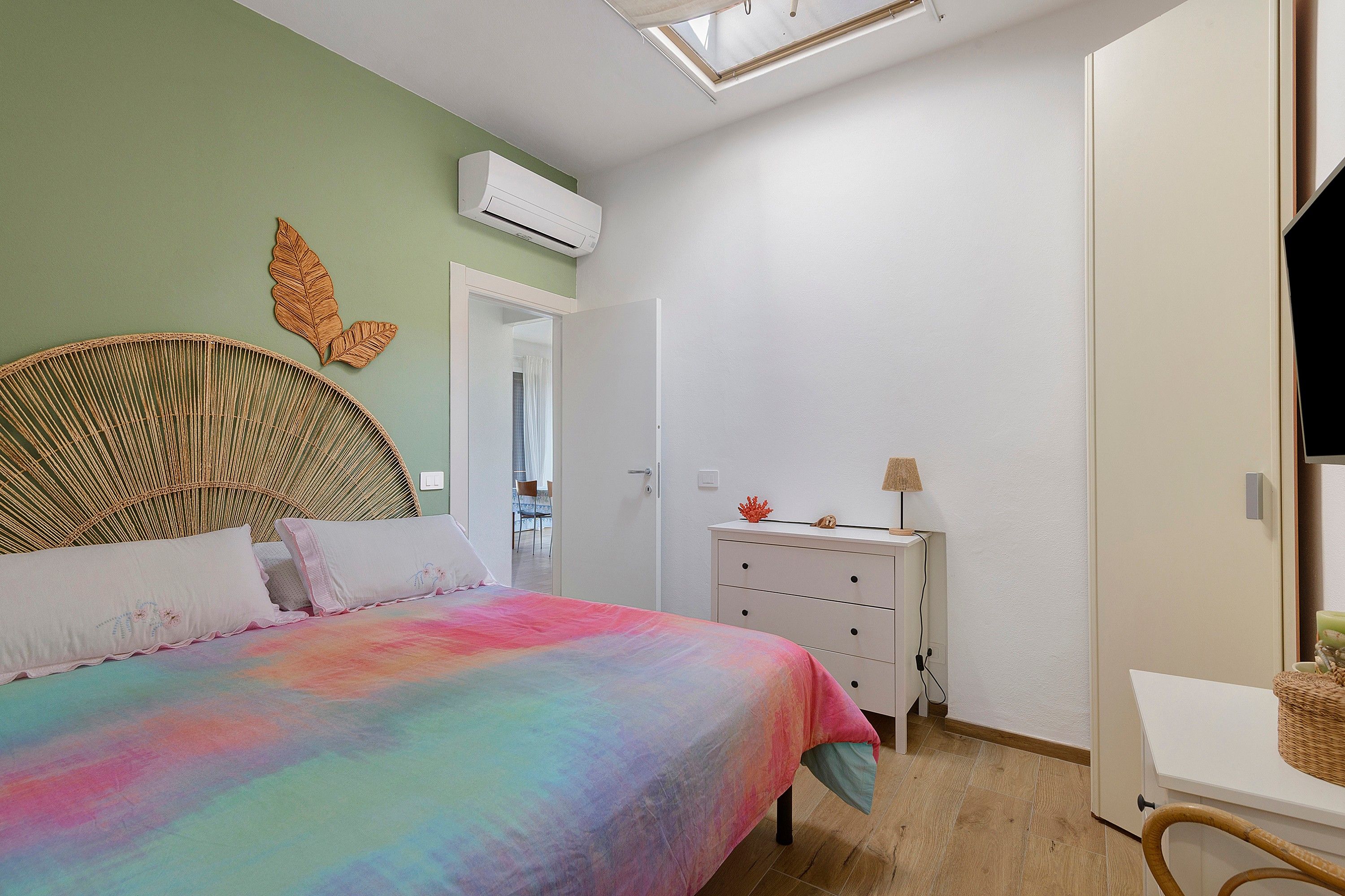 Un dormitorio con cama, cómoda, espejo y puerta que da a otra habitación.