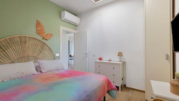 Un dormitorio con cama, cómoda, espejo y puerta que da a otra habitación.