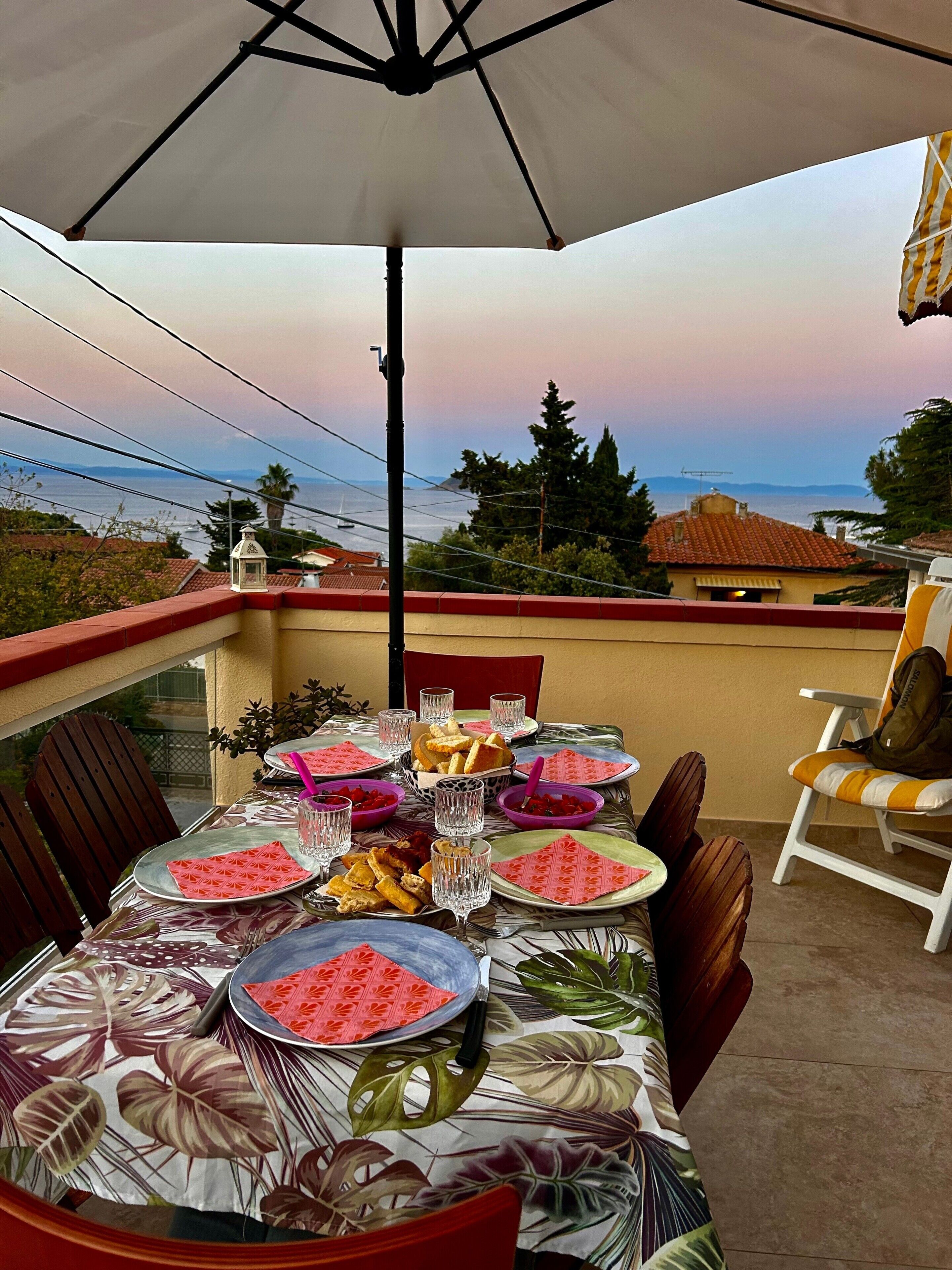 Area pranzo all'aperto con tavolo apparecchiato per quattro, con vista panoramica.