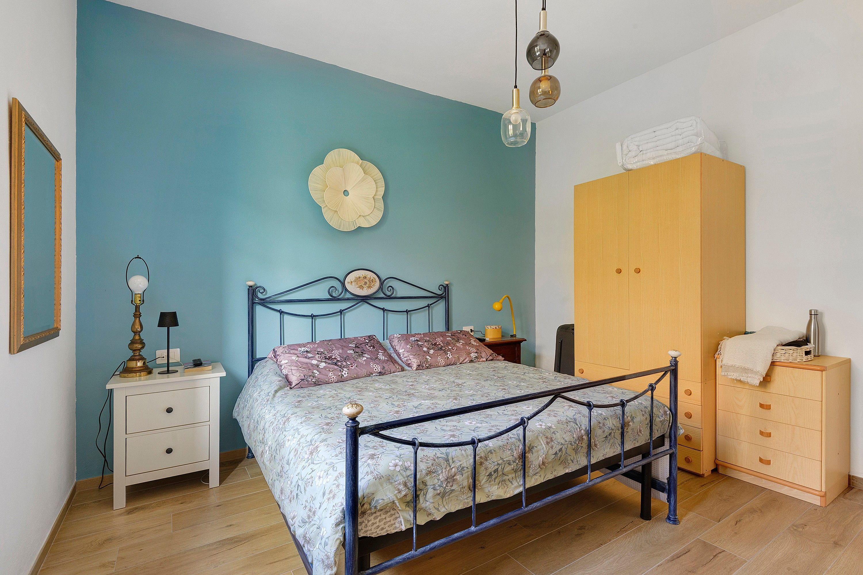 A bedroom with a bed, bedside tables, a wardrobe, and a wall decoration.