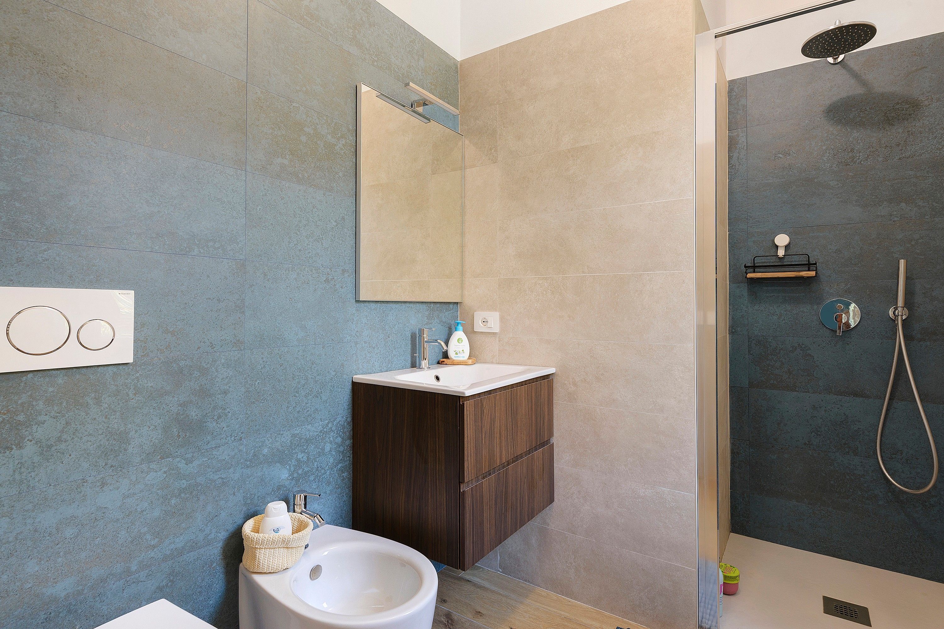 A modern bathroom with a shower, sink, and mirror.