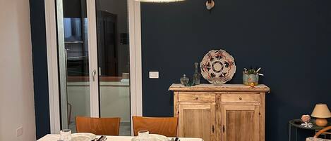 A dining area with a table set for four, chairs, a wooden cabinet, and a hanging light fixture.
