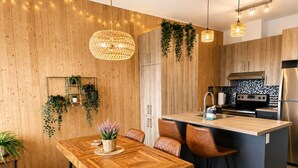 Et moderne køkken med en træø, barstole, hængende lamper og en integreret komfur.