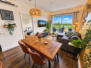 Ein modernes Wohnzimmer mit einem Holzesstisch, gemütlicher Sitzgelegenheit und einem Balkon mit Blick.
