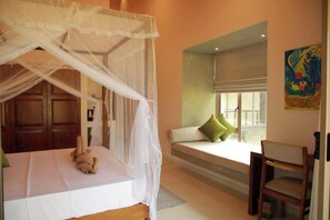 A bedroom with a canopy bed, a window seat with cushions, and a painting on the wall. - ONA Garden Villa: Double Room with Balcony (Galle)