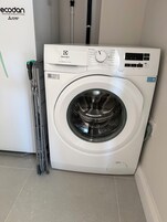 Una lavadora de carga frontal con panel de control, un código QR y una etiqueta que indica que es el modelo 600 SENSICARE de 10kg.