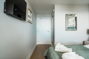 A hotel room with a bed, a TV, a door, and a mirror.