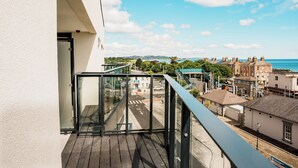 A balcony with a view of a coastal town, including buildings and a clear sky.
