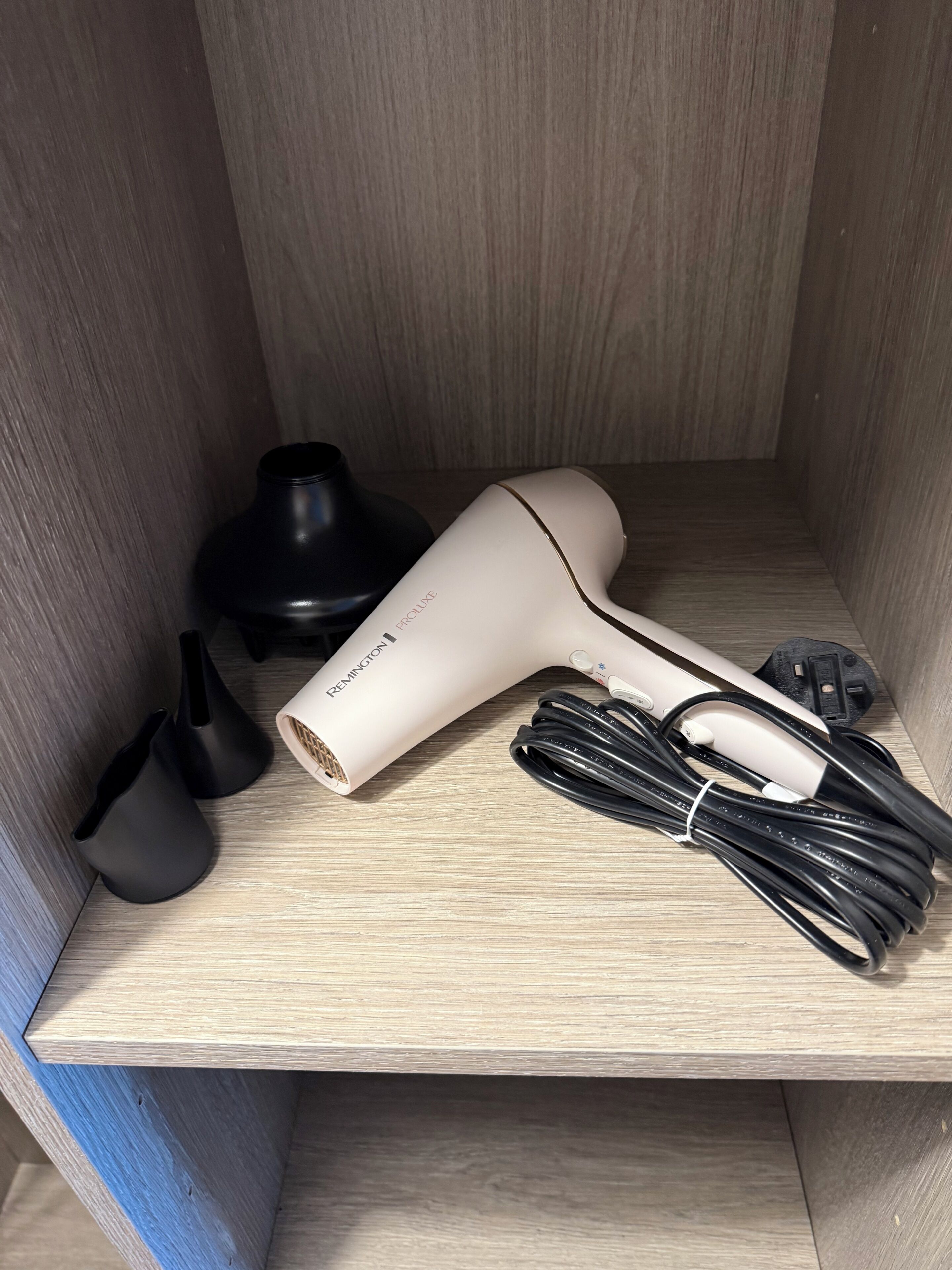 Un asciugacapelli e i suoi accessori su un ripiano di legno.