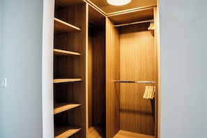 A walk-in closet with wooden shelving and a hanging rod.