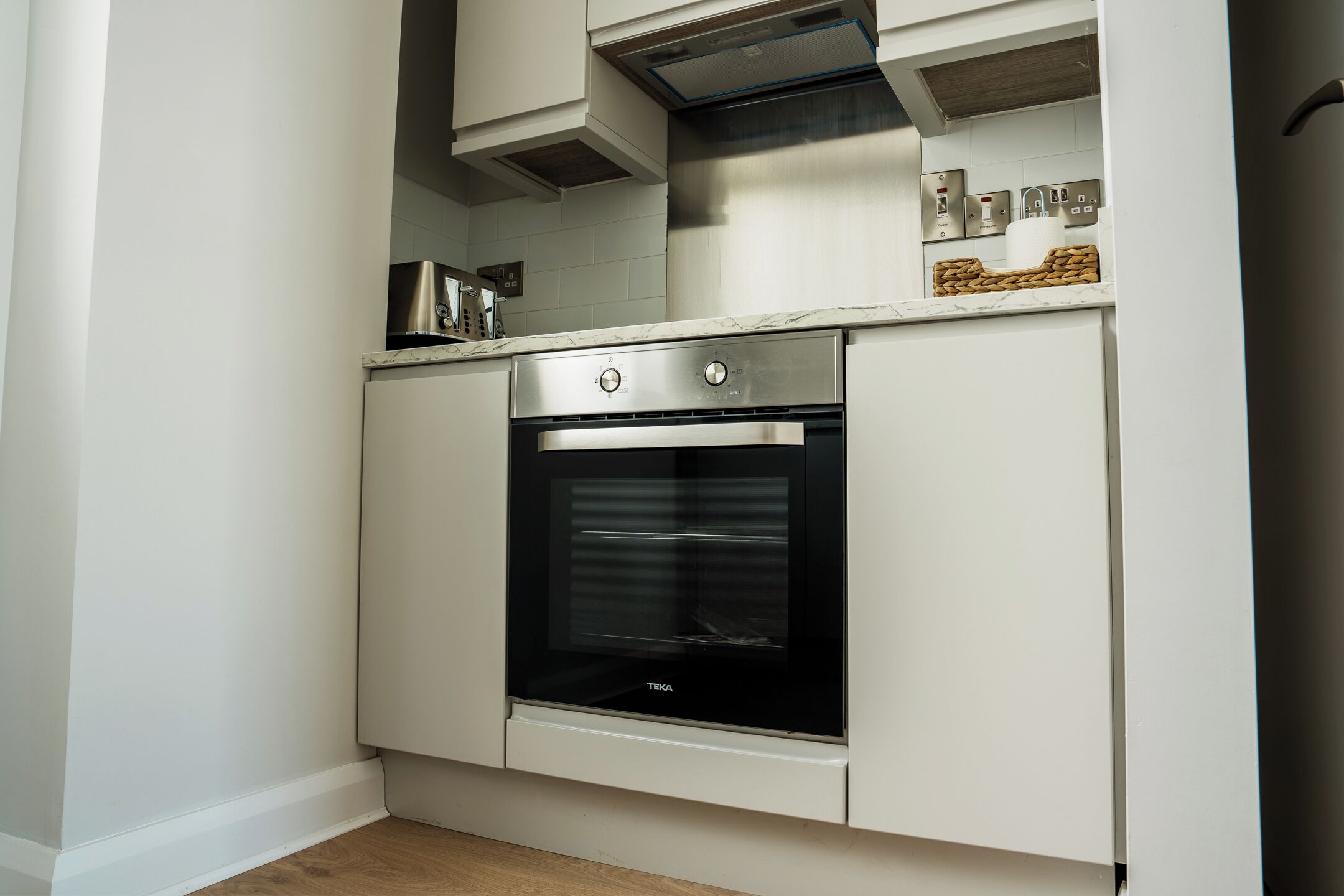 Een kleine keuken met een inbouwoven, een magnetron en een kookplaat.