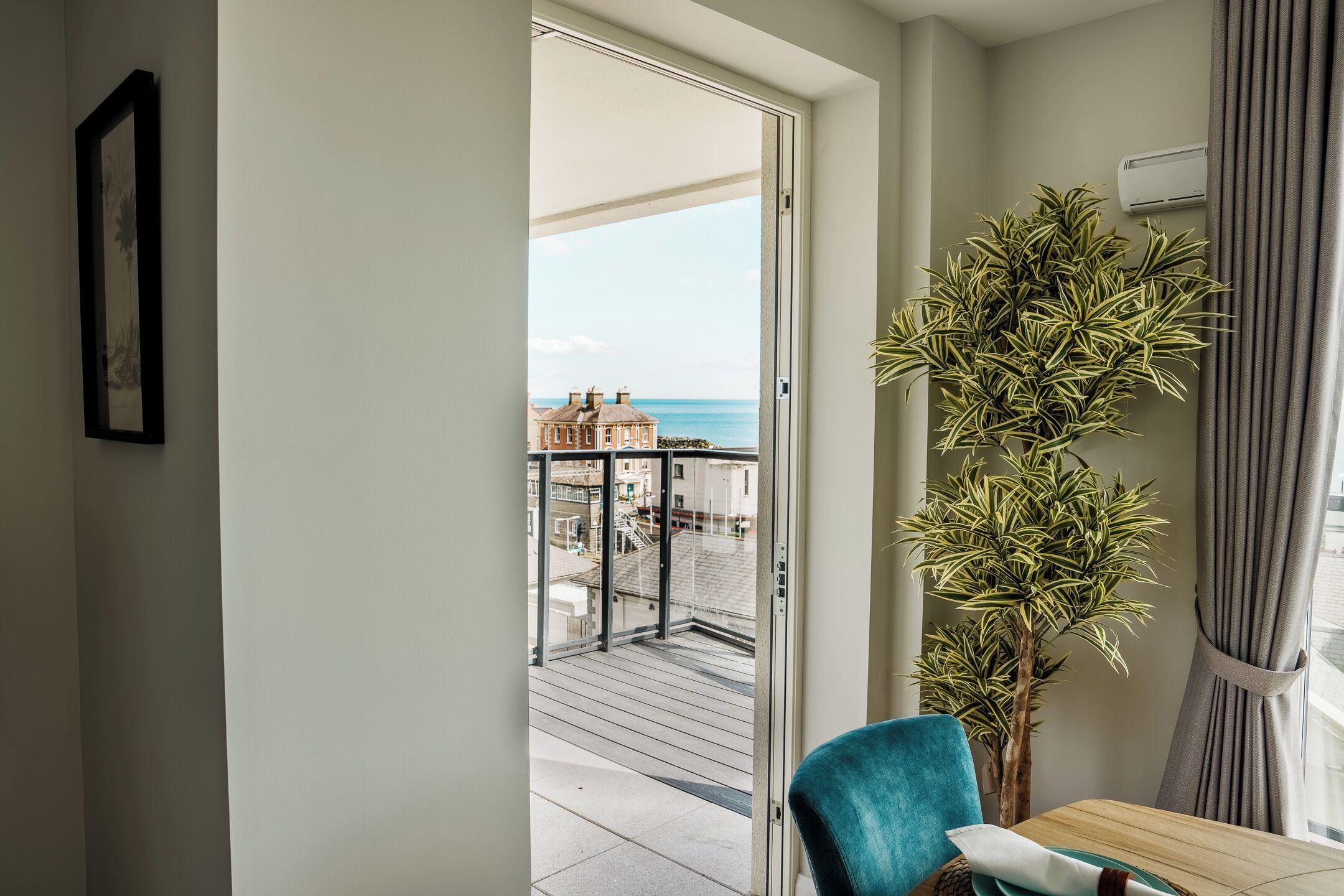 Une pièce avec vue sur la mer, une plante en pot et une table avec une chaise.