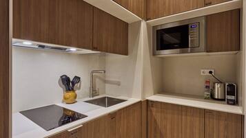 Una cocina moderna con armarios de madera, un lavamanos de acero inoxidable, un microondas y un hervidor.