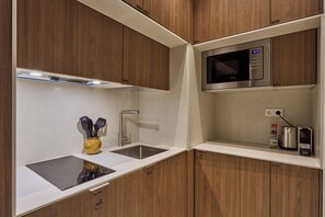 Una cocina moderna con armarios de madera, un lavamanos de acero inoxidable, un microondas y un hervidor.