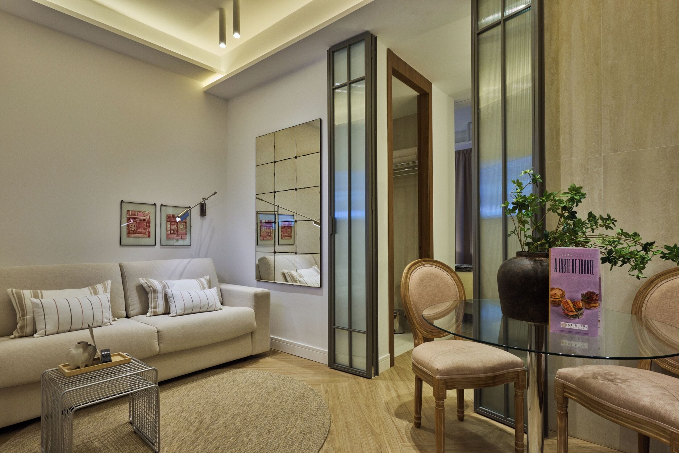 A modern living room with a sofa, chairs, a coffee table, and a glass partition.