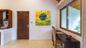 A room with a wooden door, a dining table with chairs, a window with a view, and a wall-mounted painting. - ONA Garden Villa: Deluxe Suite (Galle)