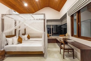 A bedroom with a four-poster bed, a desk, and a window with blinds. - ONA Garden Villa: Deluxe Suite (Galle)