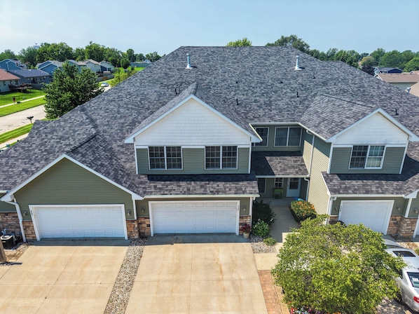 A two-story residential house with a garage, a driveway, and a well-maintained lawn.